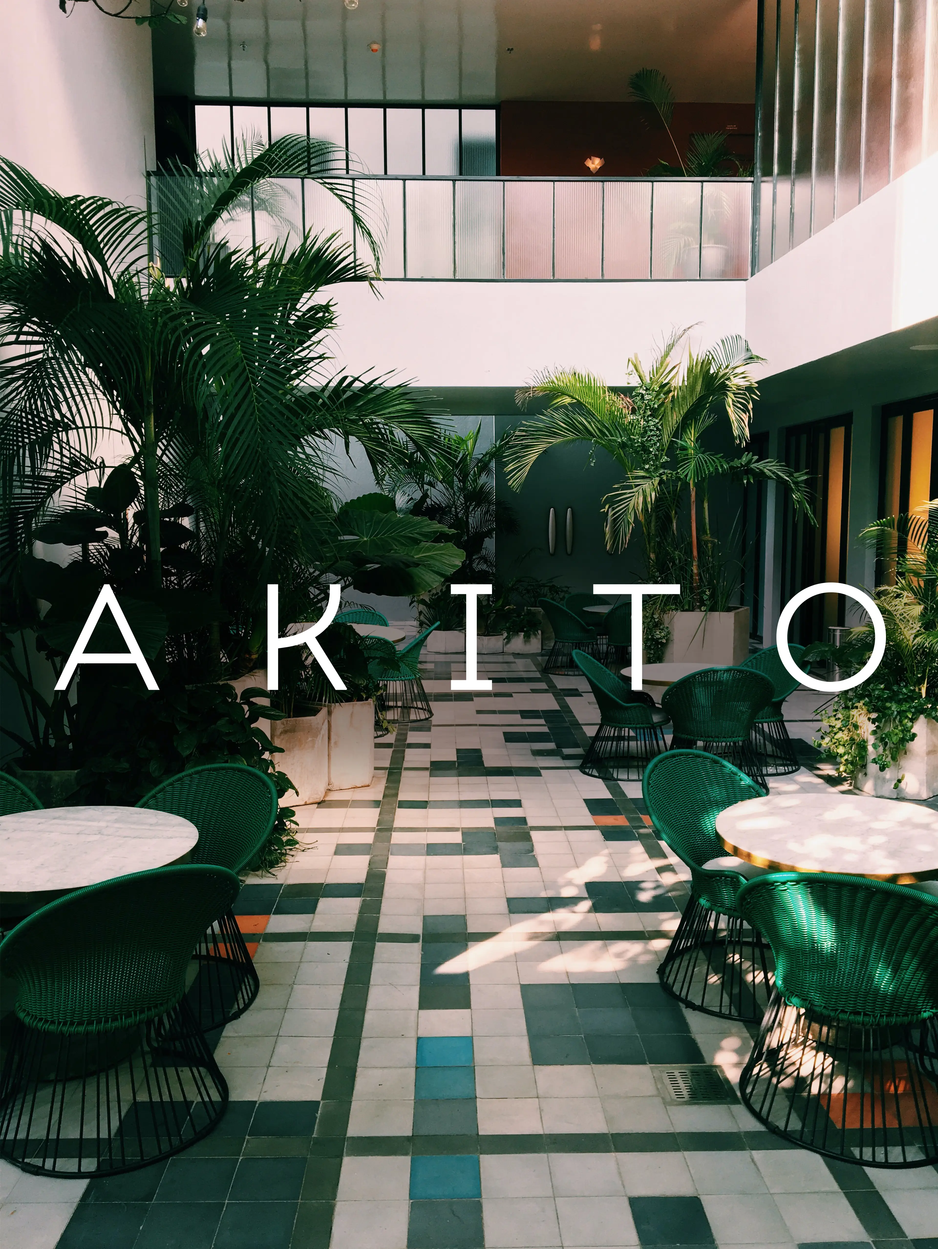 Tables and rattan chairs on a marble floor surrounded by green plants