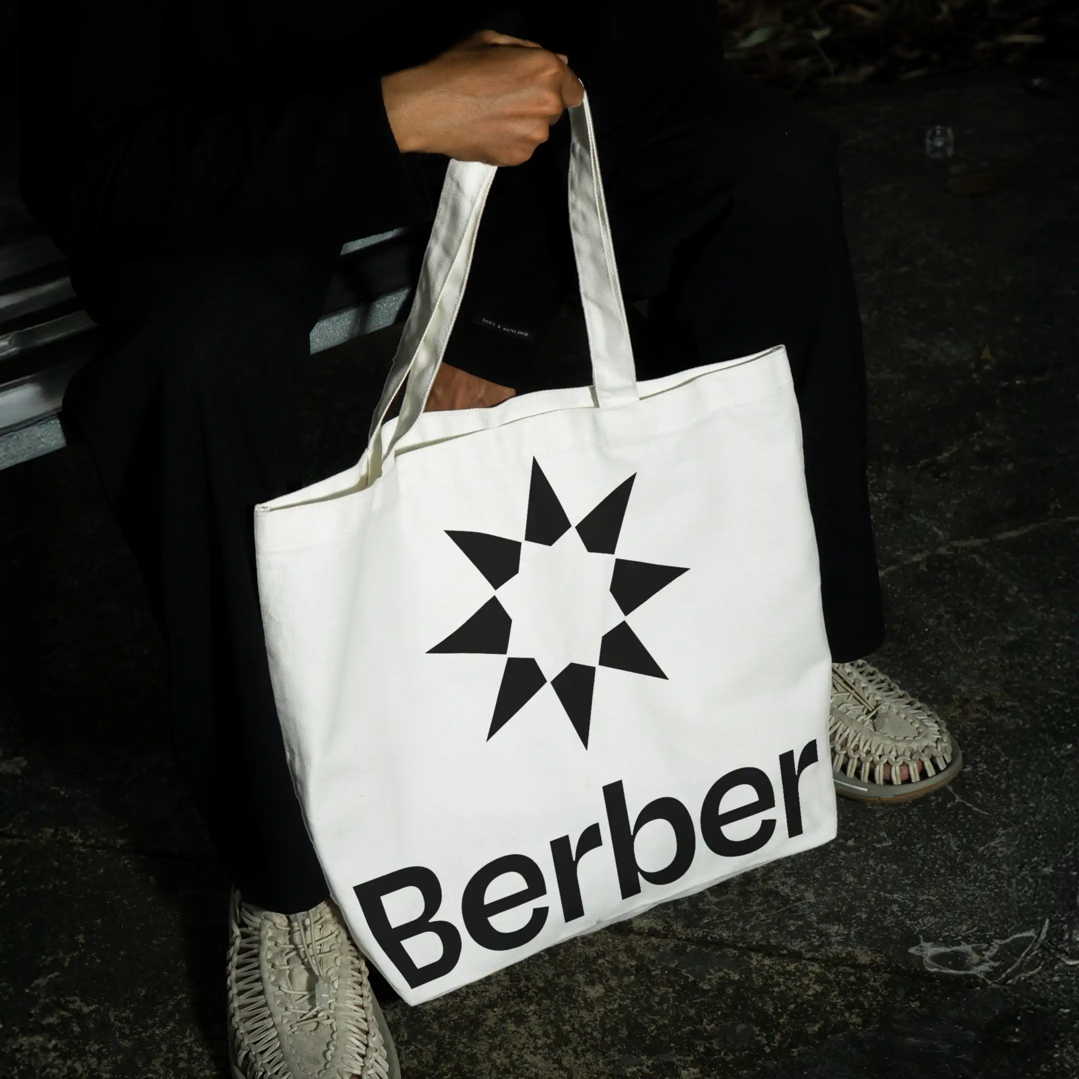 Person holding Berber skincare branded tote bag with star logo, fashion accessory.