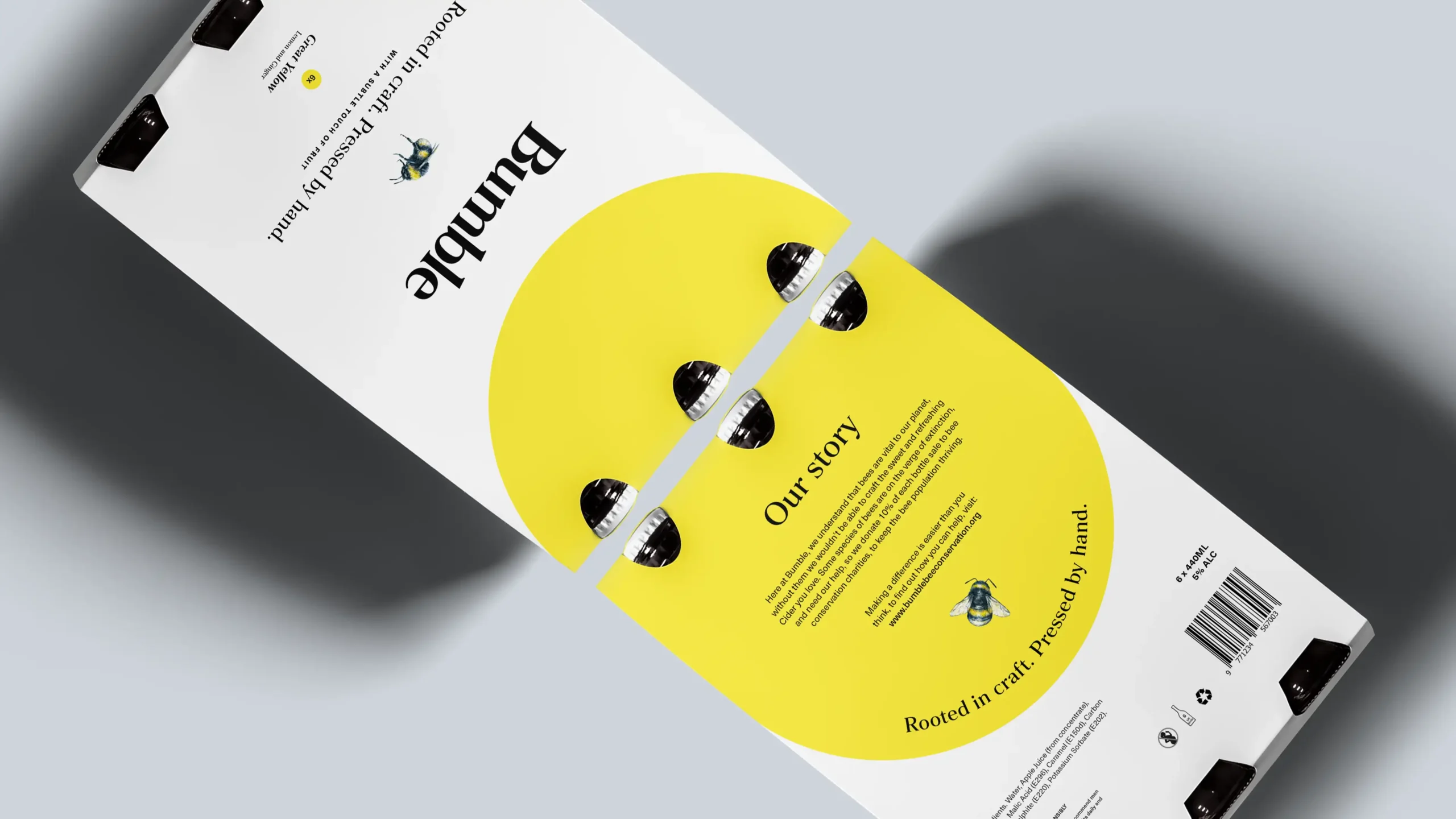 Close-up, angled view of a yellow 6-pack cider packaging, showing the front and back designs of the packaging.