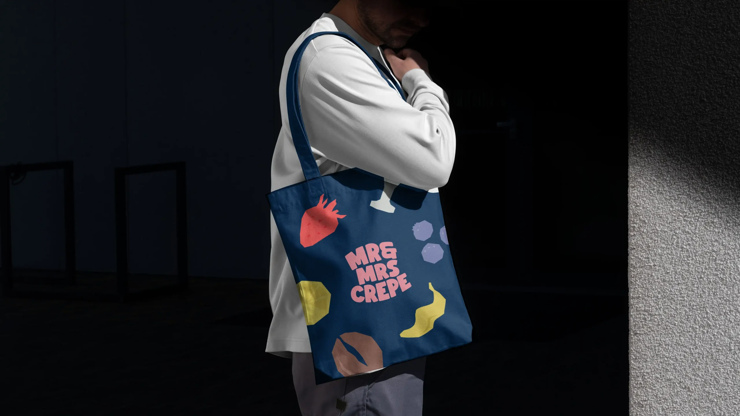 MrandMrsCrepe_Showcase_011 Person holding a Mr & Mrs Crepe branded tote bag with playful food illustrations.